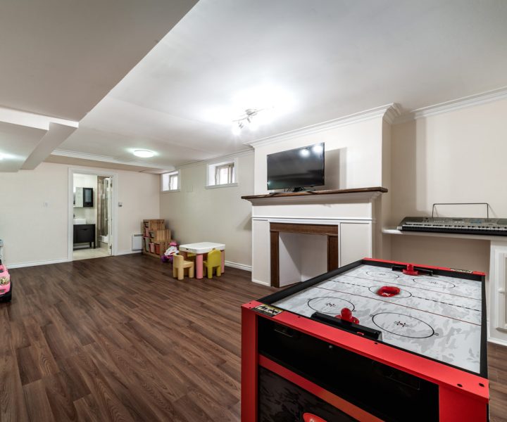 Fully remodeled basement featuring rich wood flooring and built-in entertainment areas, perfect for family leisure and activities.