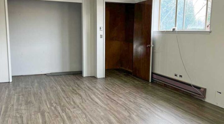 Gray wood plank flooring installed in a bedroom by Simple Floor Solutions