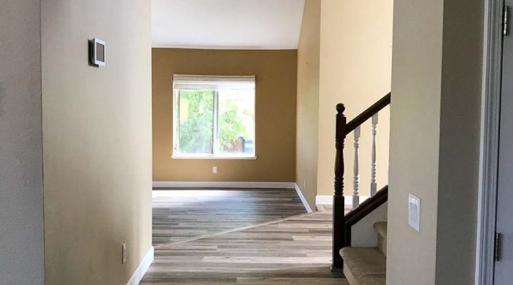 Gray plank flooring in an open hallway near a staircase with carpet runner