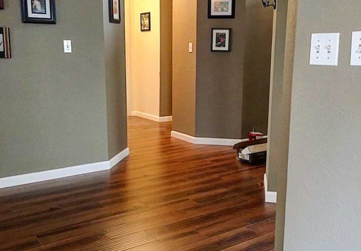Rich medium-brown hardwood flooring in a corridor with framed art and gray walls