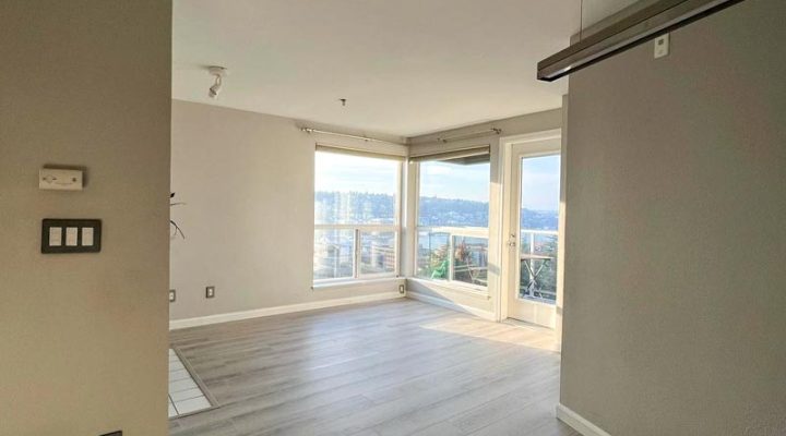 Light gray luxury vinyl plank flooring in an open condo with Seattle-area city views