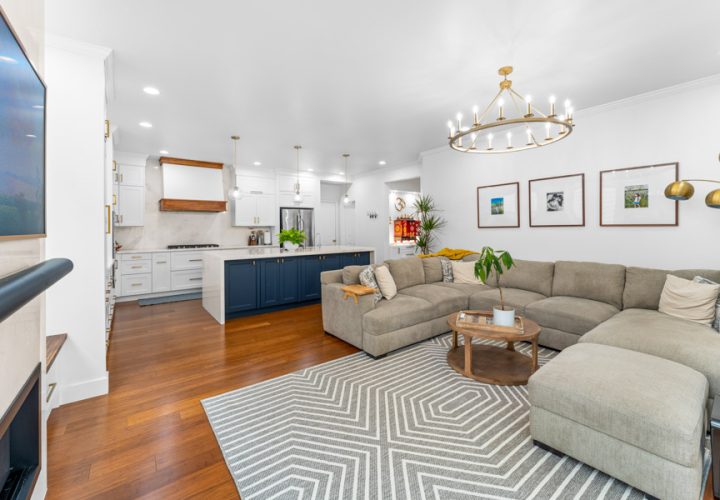 Open-concept living room and kitchen with hardwood flooring and a navy kitchen island