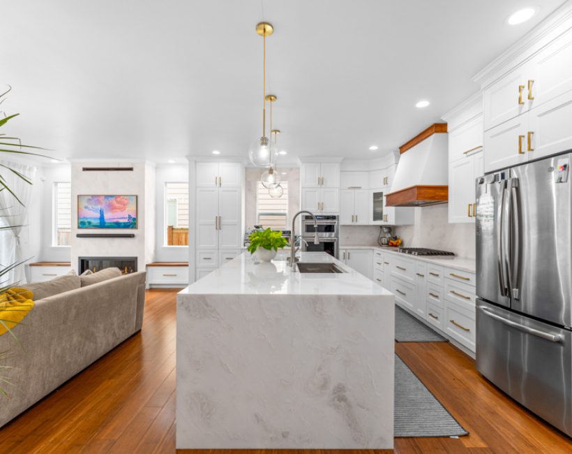 Modern white kitchen with marble waterfall island and hardwood flooring by Simple Floor Solutions in Covington, WA