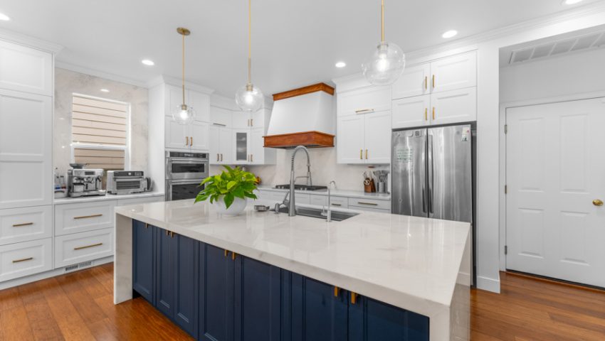 White kitchen with navy blue island, oak range hood, and dark hardwood plank flooring