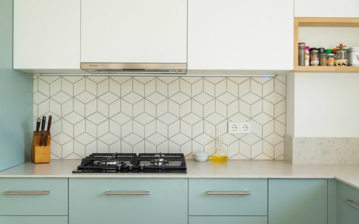 Scandinavian style kitchen with geometric backsplash and blue and white cupboards
