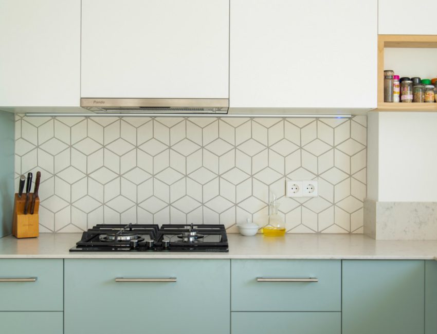 Scandinavian style kitchen with geometric backsplash and blue and white cupboards
